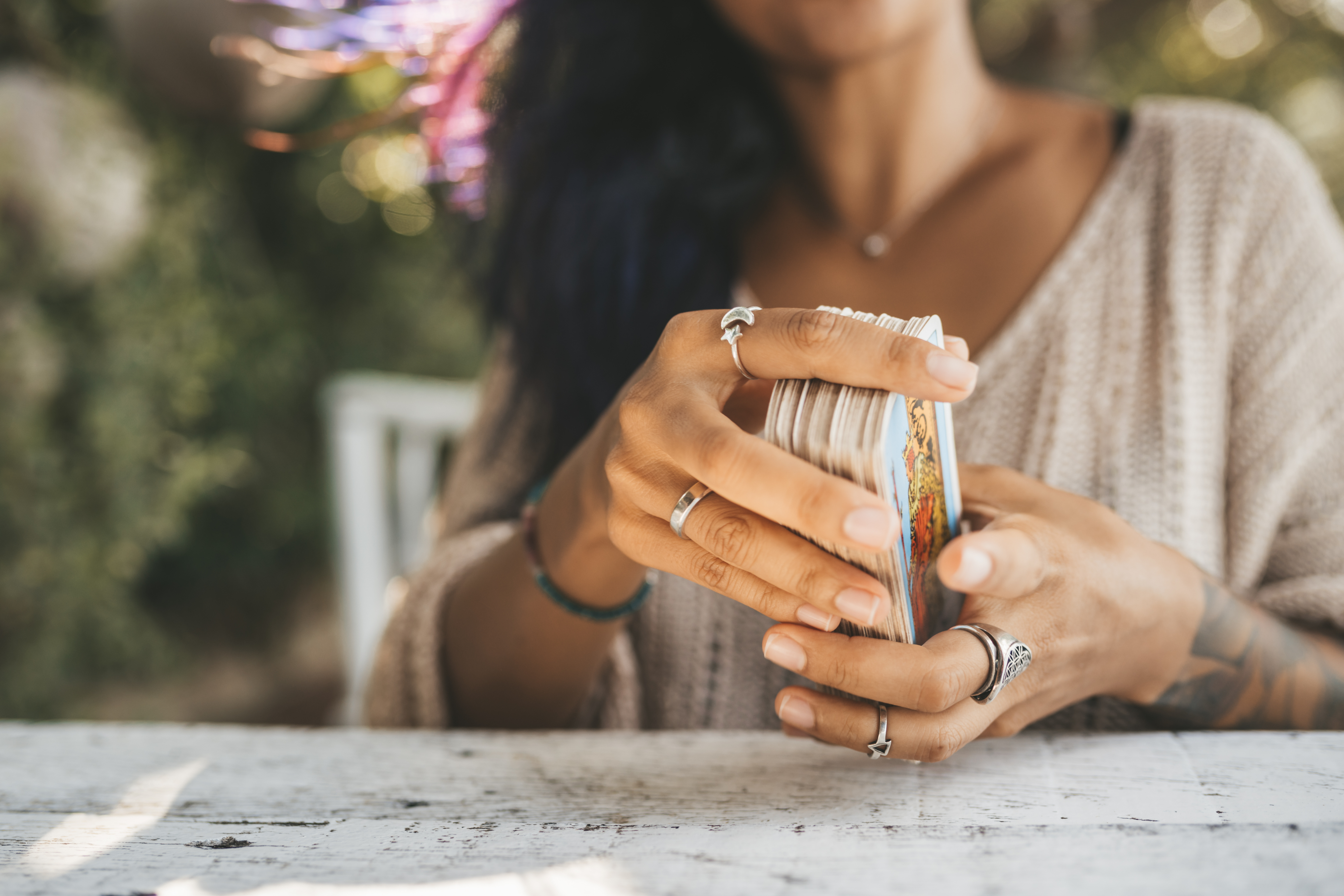 uma mulher segurando varias cartas de tarot em suas m�os sentada em uma cadeira.