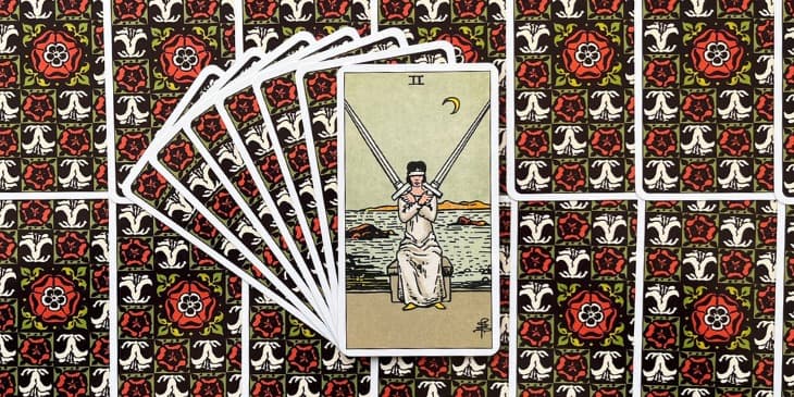 uma mulher vendada, sentada e segurando duas espadas cruzadas. A venda nos olhos sugere a ideia de cegueira ou obstru��o da vis�o, simbolizando uma necessidade de isen��o ou imparcialidade. As espadas s�o elementos de ar, associadas ao reino do intelecto e da comunica��o, indicando que a decis�o a ser tomada deve ser ponderada com cuidado e racionalidade. O fundo da carta frequentemente mostra um mar agitado, refor�ando o tema de instabilidade e as emo��es turbulentas que podem acompanhar momentos de escolha. No entanto, apesar das ondas, o c�u por tr�s da figura � geralmente calmo e de um azul claro, simbolizando a paz e a clareza que podem ser alcan�adas atrav�s do equil�brio e da pondera��o.