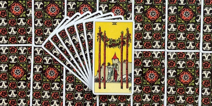 carta mostra quatro paus firmemente plantados no solo, formando uma esp�cie de arco triunfal, que � decorado com flores e frutas. um castelo ao fundo.