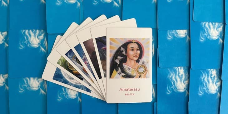 uma carta do oraculo das deusas amaterasu em cima de uma mesa com outras cartas em baixo