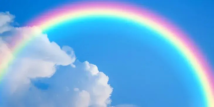 Um arco-iris em um ceu azul e com nuvens brancas