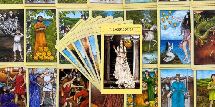 varias cartas do tarot mitologico abertas em uma mesa com a carta da sacerdotisa como principal no centro.