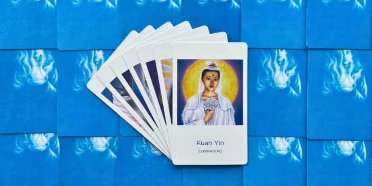 a deusa kuan yin com um vestido e veu branco segurando uma flor de lotos na mao.