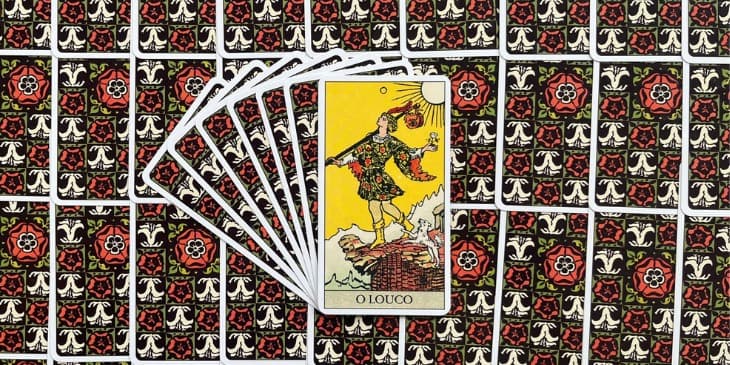 carta o louco do tarot que mostra um homem na beira de um penhasco com um cachorro branco ao seu lado