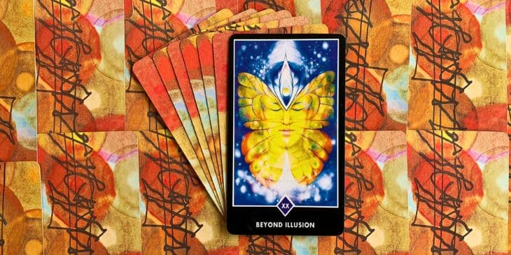 Carta do Tarot zen osho no centro da carta tem uma borboleta amarela com um rosto de olho fechado e no fundo azul e branco, a carta esta em cima de varias outras cartas.