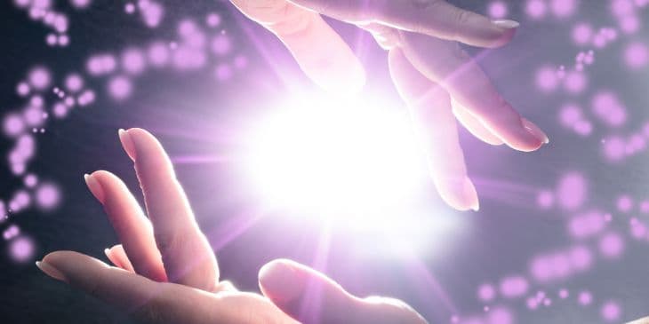 duas m�os de mulheres tocando uma bola de luz branca