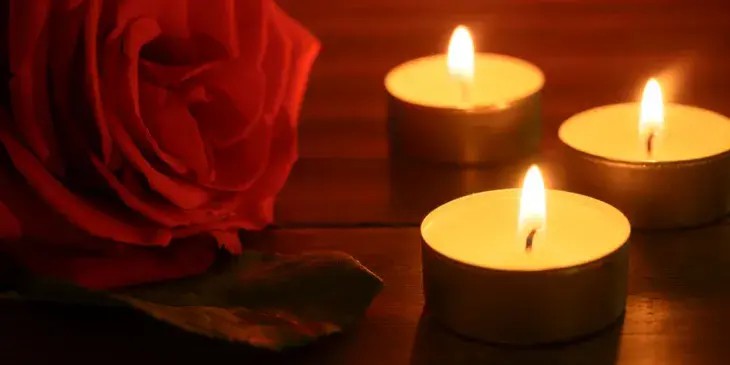 3 velas e uma rosa vermelha em uma mesa de madeira