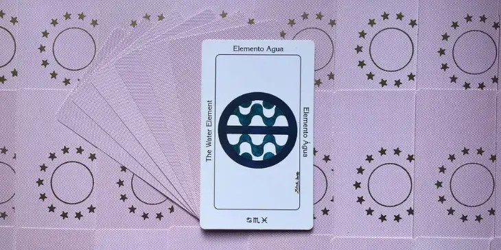 carta elemento agua do tarot sagrado dos orixas em cima de uma mesa cheia de outras cartas.