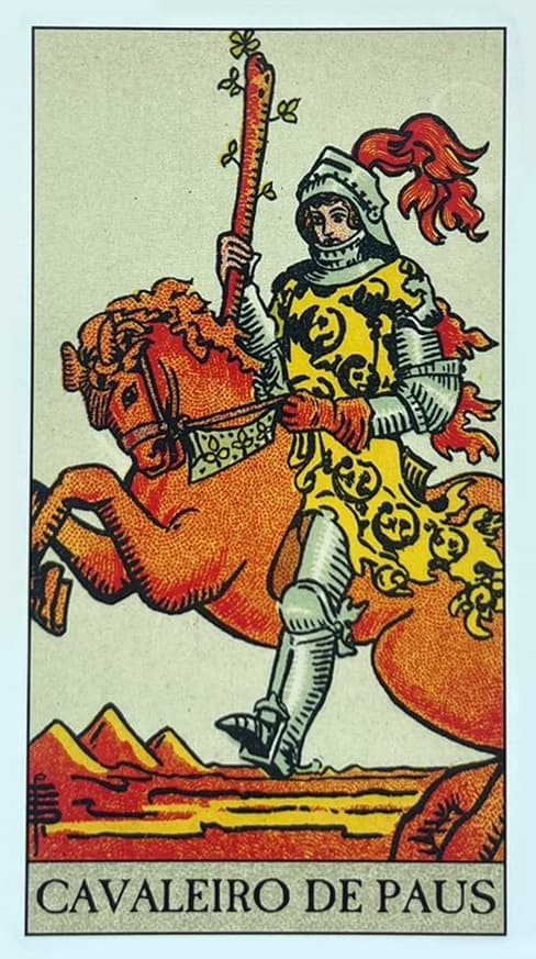 um cavaleiro medieval segurando um grande bast�o de paus em cima de um cavalo com um manto amarelo e ao fundo um deserto.