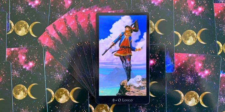 carta do tarot das bruxas O jovem aventureiro, caminhando � beira de um precip�cio, representa a disposi��o para correr riscos e a aud�cia de abra�ar o desconhecido. O vale verde abaixo e as montanhas atr�s dele simbolizam a vastid�o do caminho � frente e as conquistas passadas, respectivamente. O saco de couro que ele carrega, amarrado com um pentagrama, sugere a bagagem de experi�ncias e conhecimentos que ele leva consigo em sua jornada. O pentagrama, um s�mbolo importante no paganismo e na Wicca, representa os quatro elementos - terra, ar, fogo e �gua - e o esp�rito, sugerindo que sua jornada ser� guiada pelos princ�pios do equil�brio e harmonia. A roupa colorida do Louco reflete seu esp�rito alegre e entusi�stico, pronto para enfrentar os desafios e prazeres da viagem. A pluma vermelha em seu chap�u encarna o amor pela vida e a paix�o que o impulsiona.