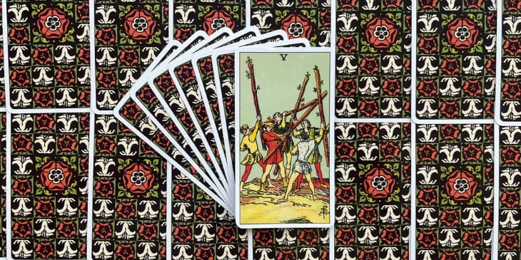 cinco homens cada um com uma cor de roupa diferente segurando um pau de arvore e parecem estar lutando