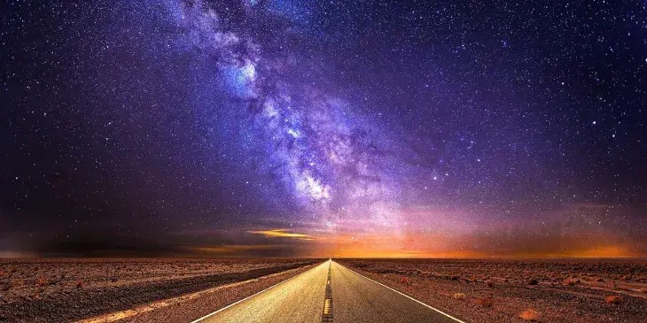 uma estrada vazia a noite com um ceu todo estrelado e lindo
