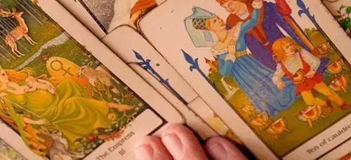varias cartas do tarot em uma mesa com uma m�o em cima.