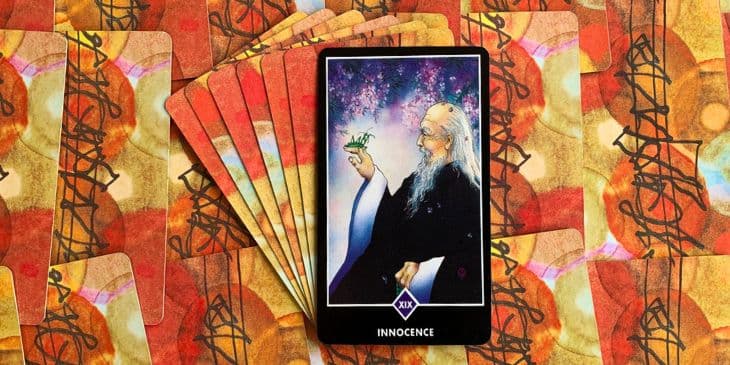 carta do taro do osho com um velho feliz segurando nos dedos um louva-a-deus verde com p�talas caindo atr�s deles