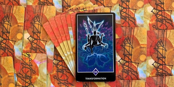 A imagem harmoniosa retrata um ser em posi��o de l�tus, transmitindo serenidade e conex�o com o divino, Nas m�os desse ser, s�o encontrados os instrumentos para a transforma��o. A espada, a serpente e a corrente e no fundo tem uma grande f�nix