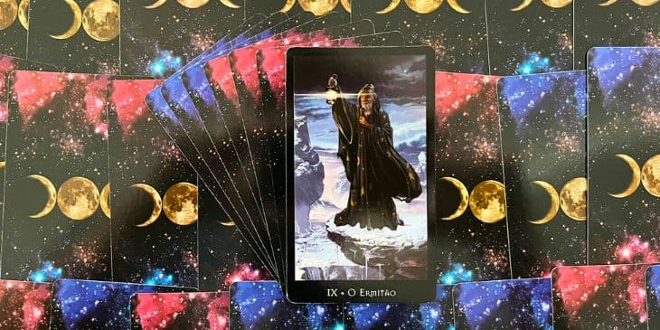 A carta O Ermit�o do Tarot das Bruxas � uma tape�aria de simbolismos e temas profundos que exigem uma an�lise detalhada para desvendar seu significado integral. Vamos explorar: O Velho Mago: A figura central desta carta, aparentemente Merlin, representa sabedoria e conhecimento acumulados com o tempo e a experi�ncia. Ele se afasta da agita��o do mundo para se concentrar na introspec��o e na busca pela verdade. O Manto Desbotado: O manto desgastado de luas e estrelas simboliza uma longa jornada de autodescoberta, introspec��o e aprendizado. A imagem sugere que a sabedoria � adquirida com o tempo e muitas vezes ap�s longas jornadas e prova��es. A Montanha: Este elemento representa a escalada solit�ria em busca de autoconhecimento e verdade espiritual. A montanha � um lugar de isolamento, mas tamb�m de clareza e percep��o elevada, simbolizando o alcance do conhecimento e a supera��o de desafios. A L�mpada: A l�mpada com a estrela de seis pontas ilumina o caminho do Ermit�o. Isso representa a busca pela verdade, tanto interna quanto externamente. A estrela de seis pontas, ou hexagrama, � um s�mbolo antigo de equil�brio entre energias masculinas e femininas, sinalizando que a verdadeira sabedoria requer um equil�brio de tais for�as. O Cajado: Representa a necessidade de suporte e orienta��o ao longo da jornada de autodescoberta. Ele sugere que, embora a jornada seja solit�ria, contamos com ferramentas e recursos internos para nos guiar. C�u Crepuscular: O c�u ao entardecer reflete o limiar entre o conhecido e o desconhecido, entre a luz da consci�ncia cotidiana e a escurid�o do subconsciente. O Ermit�o est� nessa fronteira, iluminando o desconhecido com sua lanterna de sabedoria.