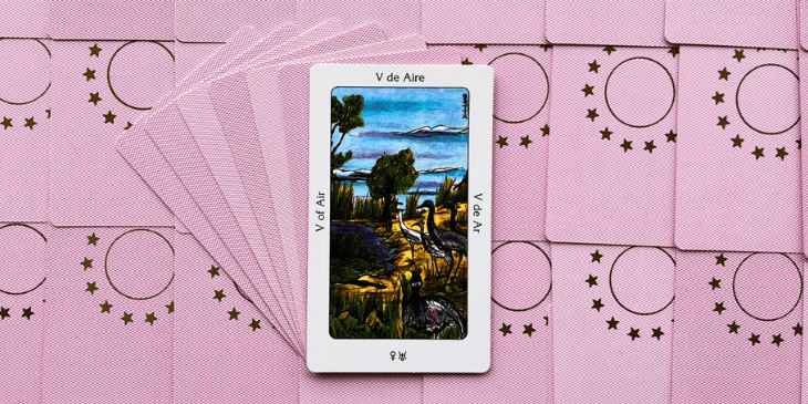 carta cinco do tarot dos orixas em cima de outras cartas