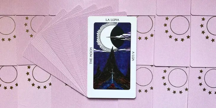 uma lua branca no ceu com nuvens em volta, uma montanha escura e uma espada enfiada no ch�o de pedra