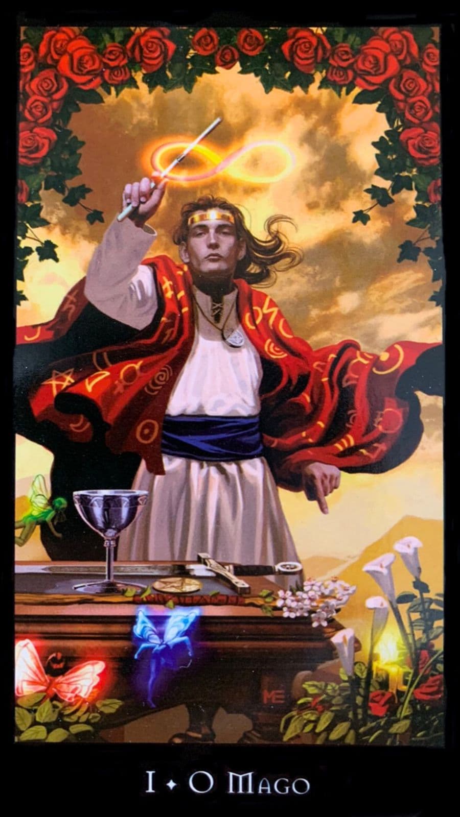 O Mago, principal figura da carta, apresenta-se vestido com um manto vermelho, uma cor intensa que simboliza a energia, a paix�o, a for�a e o poder. A postura ativa dele, de p�, indica a disposi��o para a a��o, para dar in�cio a novos projetos ou empreendimentos. Na m�o direita, o Mago segura uma varinha e desenha no c�u o s�mbolo do infinito, sugerindo a ideia de ciclos infind�veis, da eternidade e da interconex�o entre todas as coisas. A m�o esquerda, com o dedo indicador apontando para a terra, refor�a o conceito de 