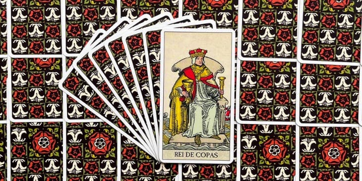 Sentado em um trono flutuante sobre as águas calmas, o Rei está diretamente associado ao elemento água, que simboliza a fluidez, a intuição e o inconsciente. O mar ao fundo é calmo, sugerindo que ele domina os sentimentos turbulentos e pode navegar com sabedoria pelas ondas emocionais da vida. O Rei segura um cálice, o objeto que dá nome ao naipe, que transborda de seu vasto conhecimento emocional e empatia. Este cálice não contém apenas água, mas sim o elixir das emoções refinadas e purificadas pelo discernimento e experiência. A roupa do Rei, geralmente ilustrada em tons de azul e cinza, simboliza serenidade, estabilidade e uma profunda conexão com o espiritual e o emocional.