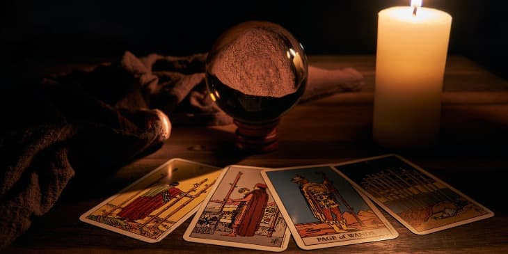 varias cartas de tarot, uma bola de cristal e uma vela branca