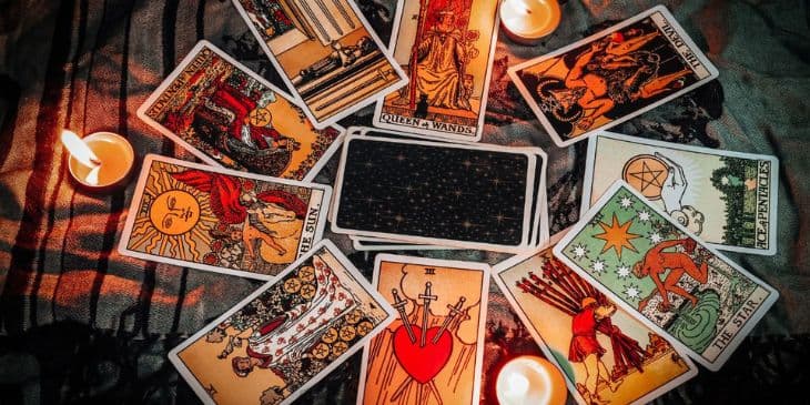 Cartas de tarot abertas em formato de circulo com 3 velas acessas em volta da mesa