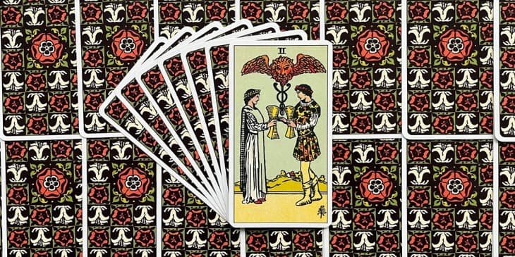 duas pessoas, geralmente um homem e uma mulher, trocando ta�as em um gesto que simboliza a troca e o equil�brio emocional. Acima das cabe�as das figuras, vemos o Caduceu de Hermes, um s�mbolo antigo associado � negocia��o, ao com�rcio e ao equil�brio. O caduceu, composto por duas serpentes entrela�adas em torno de uma vara alada, aponta para a capacidade de reconciliar for�as opostas para criar harmonia. A presen�a de um le�o com asas no topo do caduceu traz um elemento adicional de paix�o e for�a, sugerindo que a uni�o representada na carta � n�o apenas pac�fica, mas tamb�m poderosa e vital.