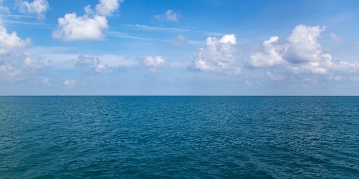 O mar azul bem calmo e um c�u cheio de nuvens brancas
