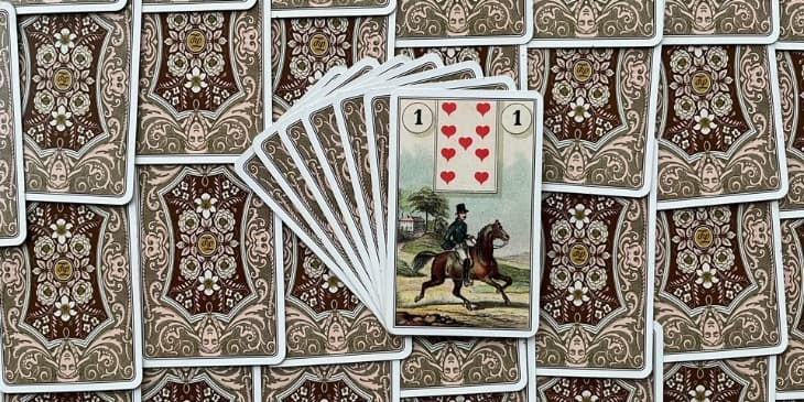 uma carta do baralho cigano que mostra a imagem de um cavaleiro em cima de um cavalo em uma paisagem que tem uma casa no fundo, uma arvore com o tronco fino e um caminho de terra batida.